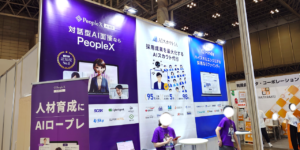 Trade show booth for PeopleX with large purple banners about AI interviews; staff in matching purple shirts nearby.