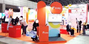 IT展示会に出展されたRIMOのブース。自社ナレッジを活用するAIエージェントによる業務自動化のデモや、Copilot活用に関するパネル掲示の様子。