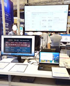 展示会場におけるDatabricksのデモ展示。画面上にAI-BI Sales & Marketing DashboardやDatabricksの全体図アーキテクチャが表示されている様子